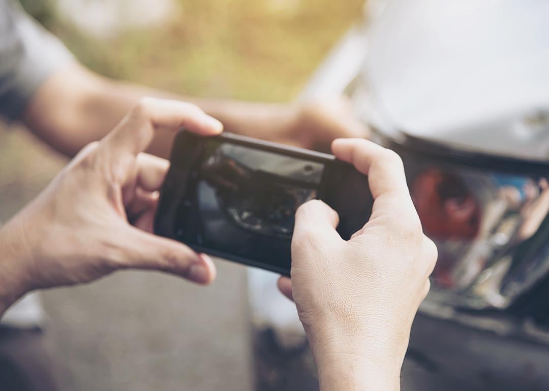 An insurance agent taking a photo of a car's damage.