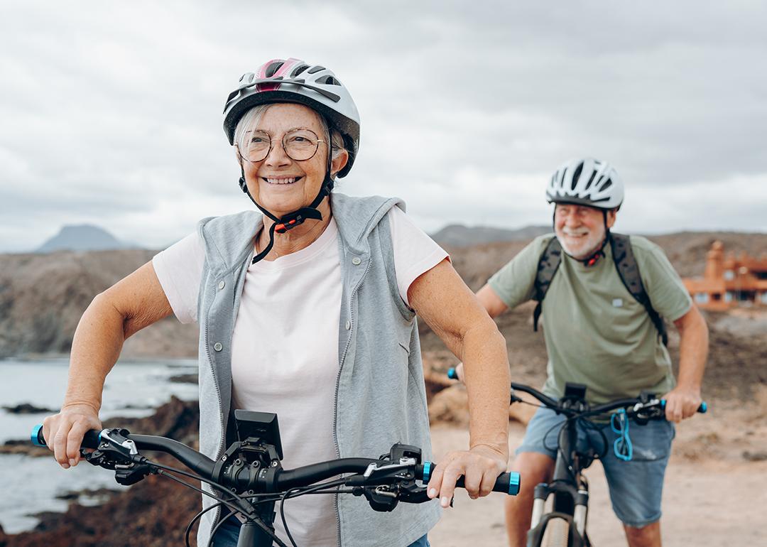 A senior couple riding their bikes on the beach.