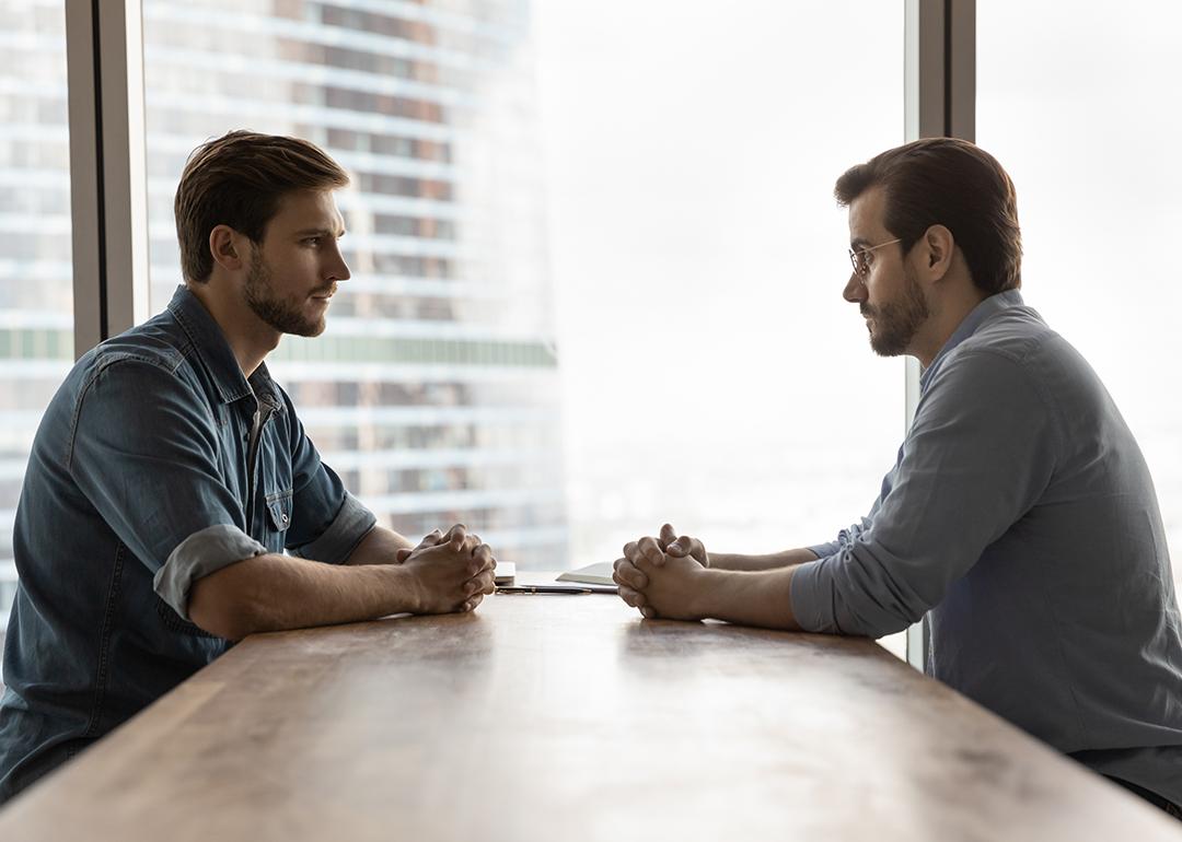 Two businessmen sitting across a table from each other engaged in discussion.