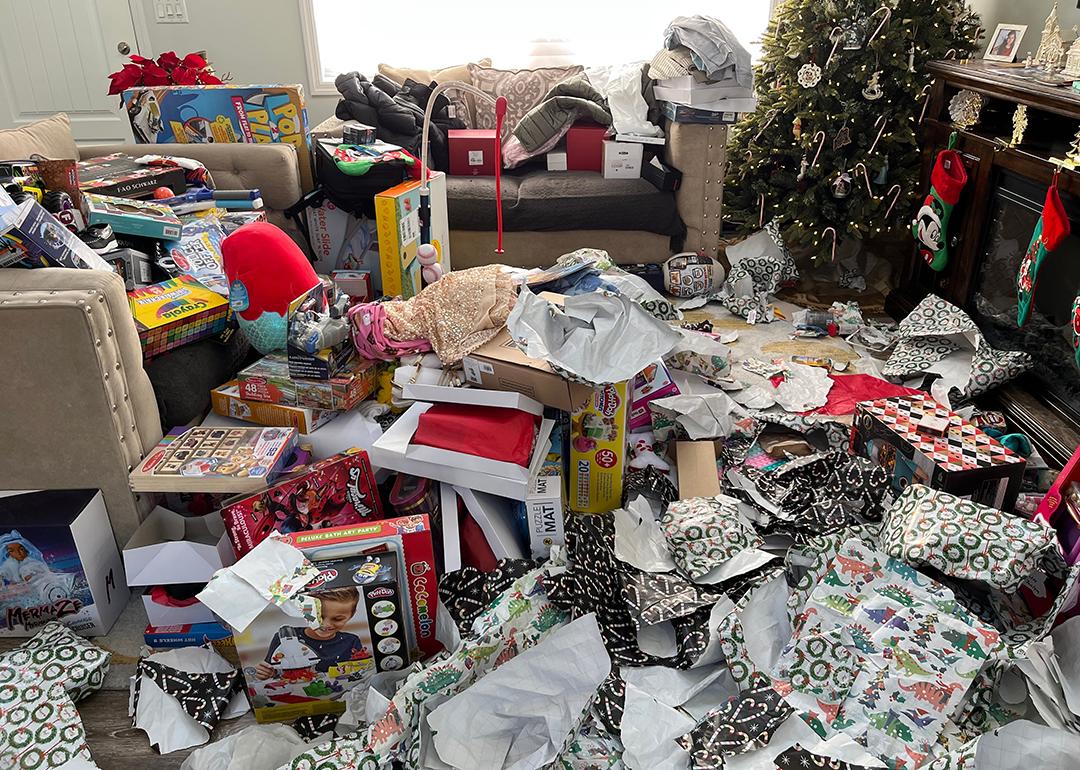 Piles of messy packaging and opened presents in a living room during Christmas morning.