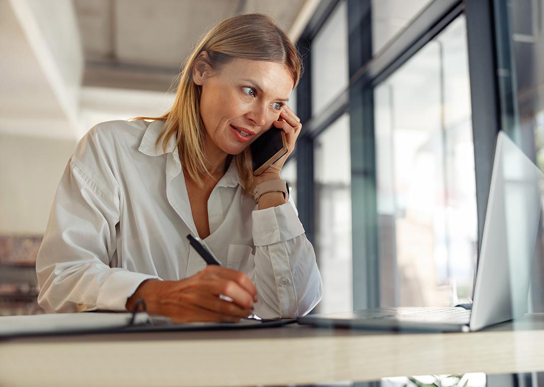 A businesswoman writing down notes as she talks to someone on the phone.