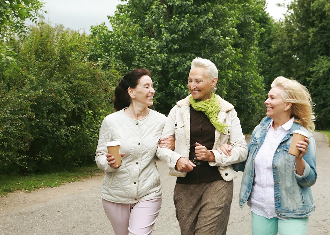 Three elderly women walking in the park.