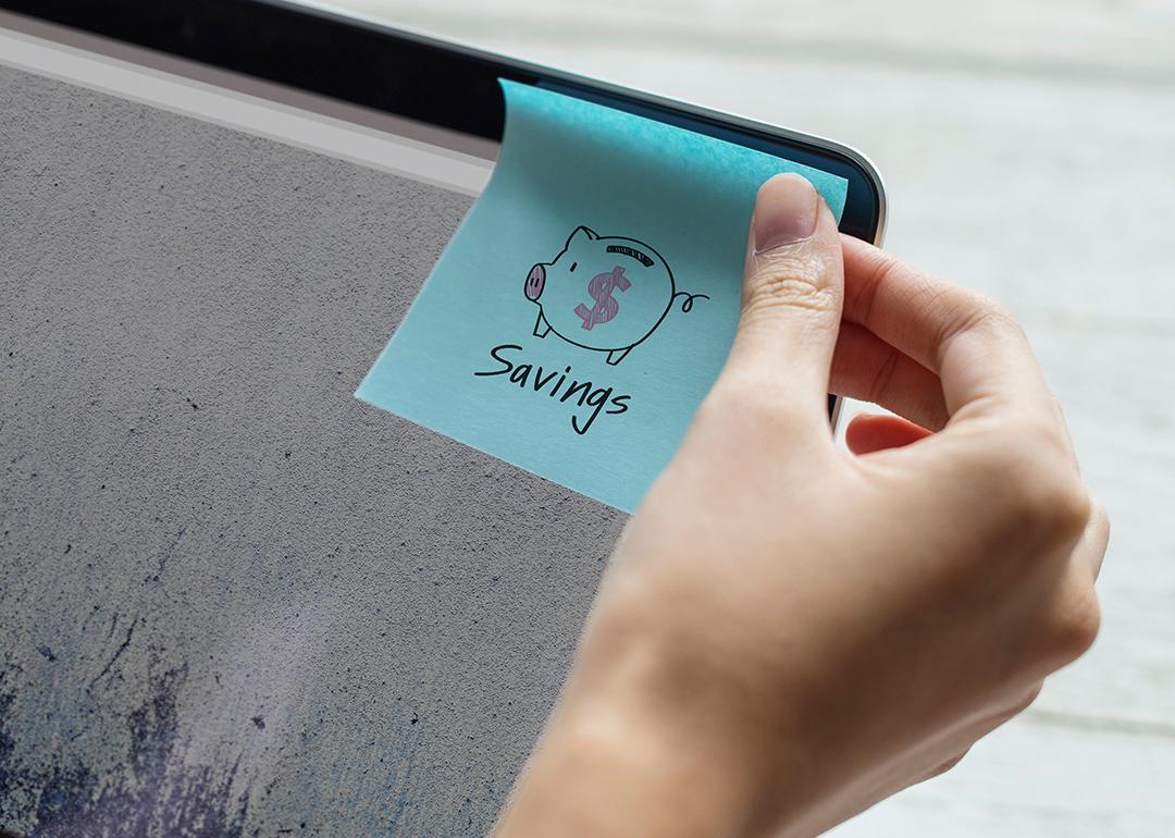 A person sticking a savings note on a computer screen.