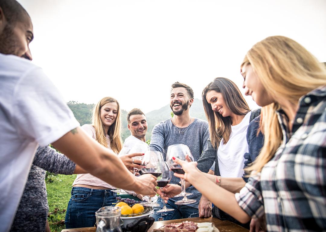 A group of friends making a toast with wine glasses while having a meal outdoors.