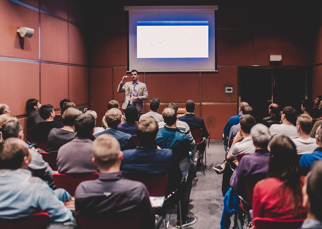 An audience in a conference room listening to a speaker.