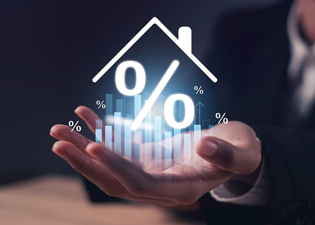 A real estate agent's hand holding up a hologram of a home with percentage figure.