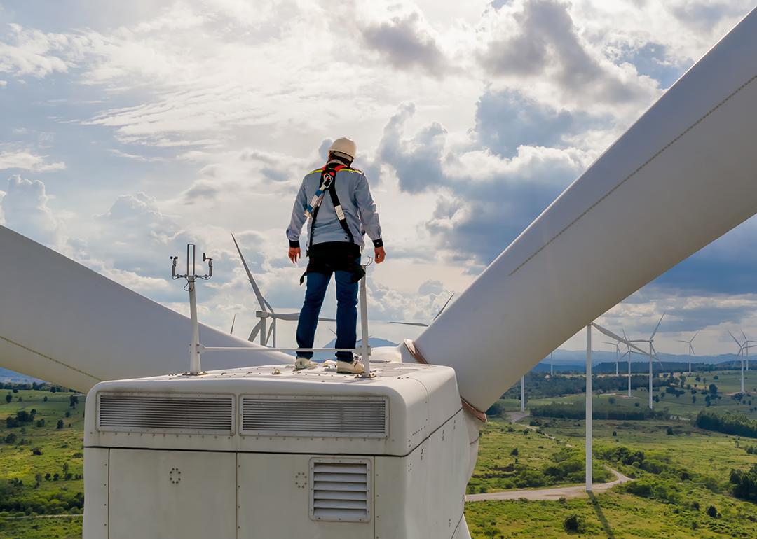 A windmill engineer on top of a wind turbine for inspection.