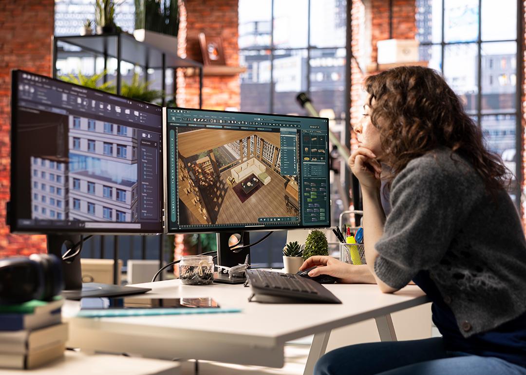 A professional interior designer using two monitors to work on a project.
