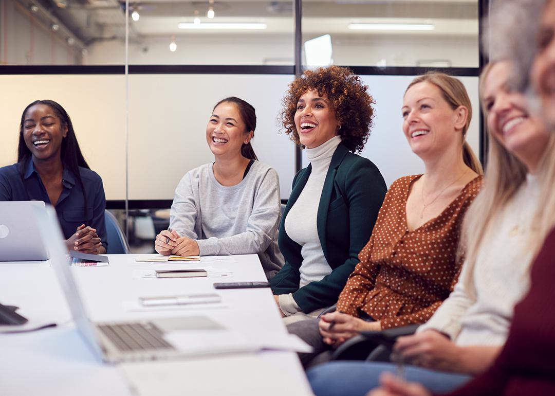 A group of business women listening to a presentation in a meeting room.