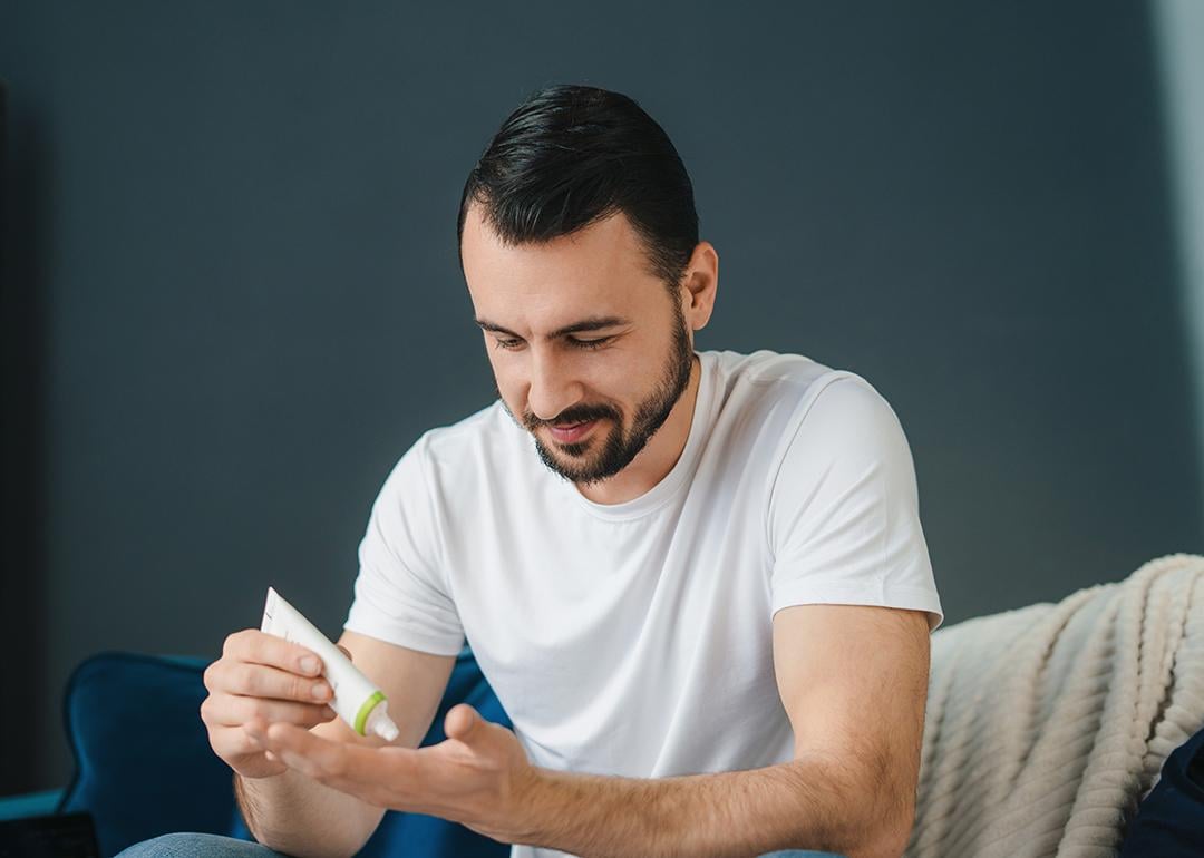 A man squeezing a tube of face cream.