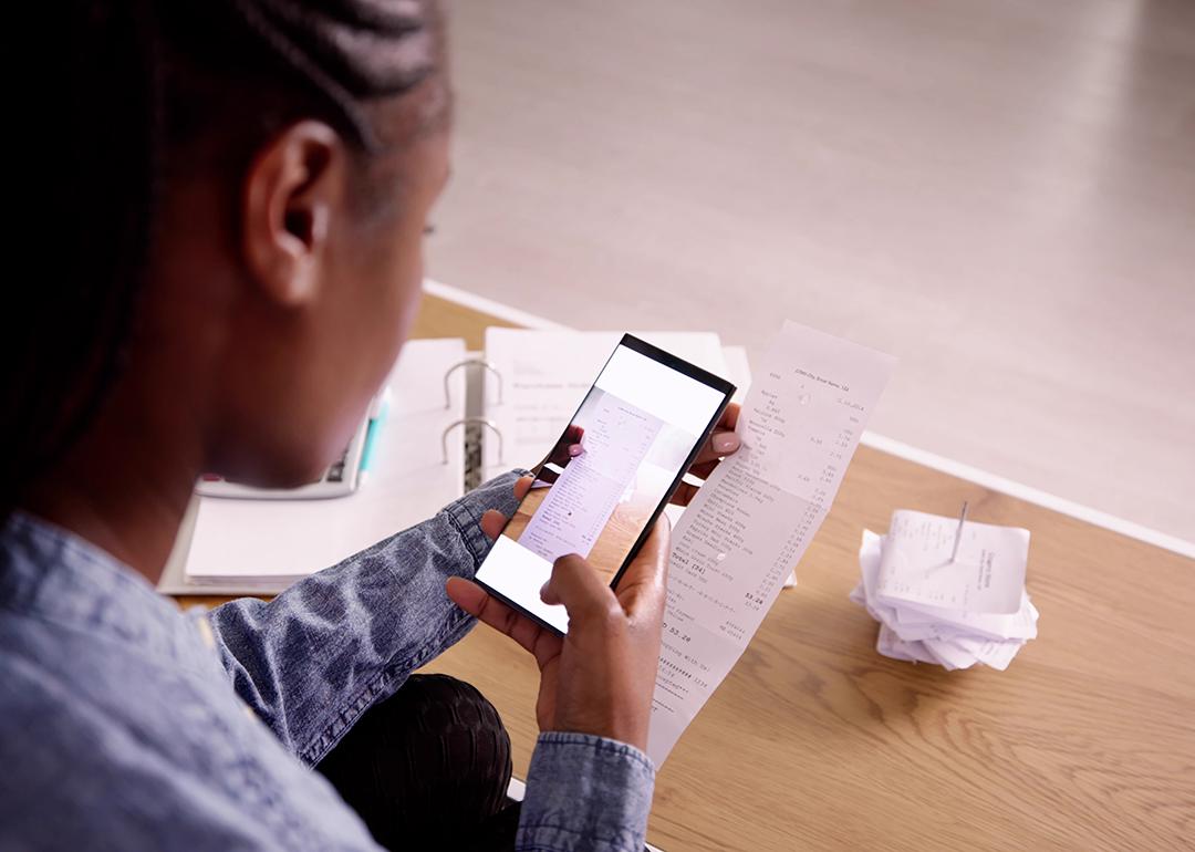A woman taking a photo of a receipt using her phone.