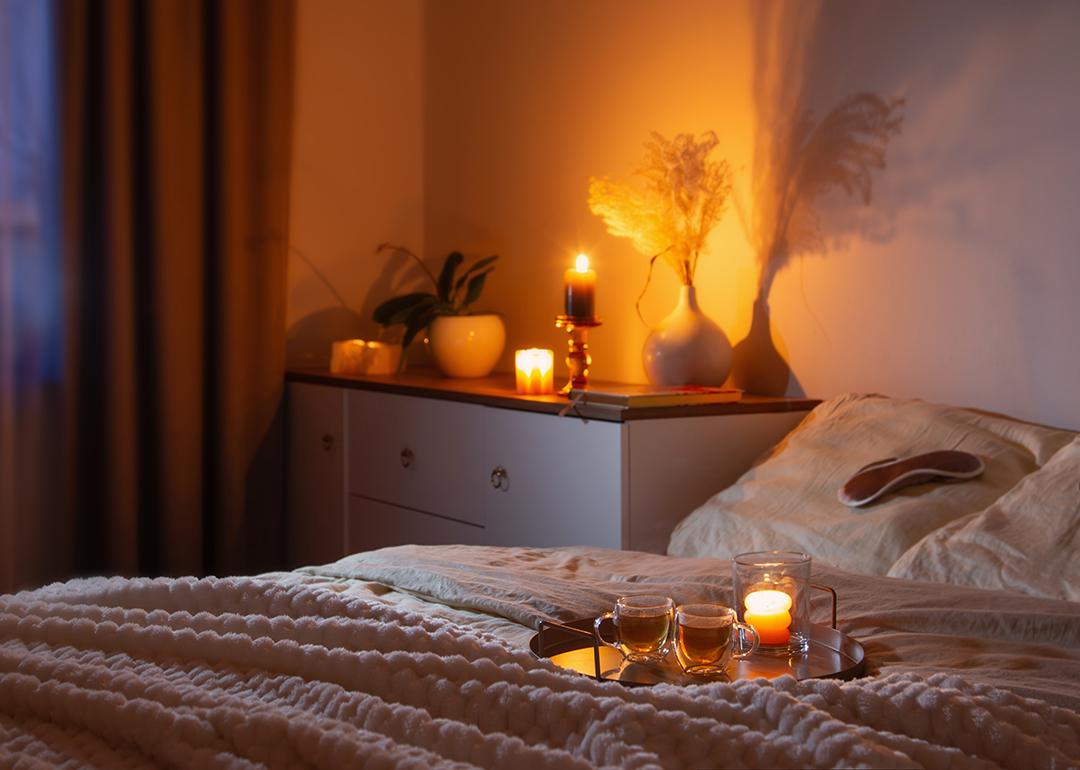 Cups of tea on a tray on a bed at night.