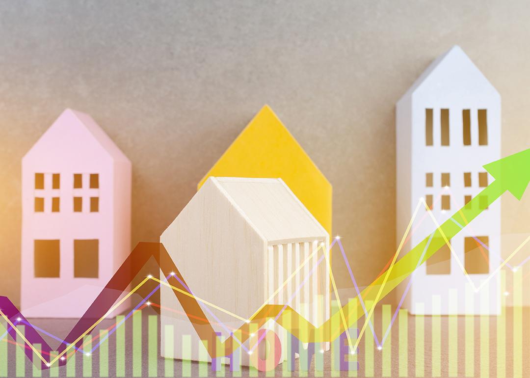 Colorful wooden figures of homes illustrated with finance chart graphics.
