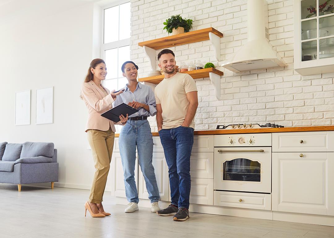 A female broker giving a young couple a tour of a house.