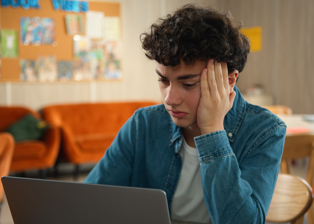 A stressed young adult sitting in front of a laptop. 