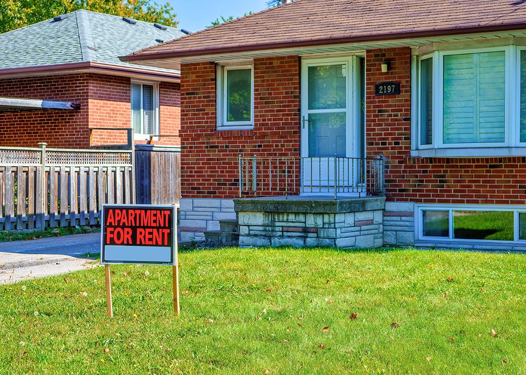 An 'apartment for rent' sign on a house lawn.
