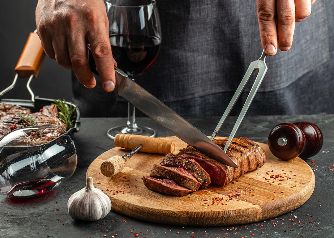 Grilled steak on a wooden cutting board and a glass of red wine.