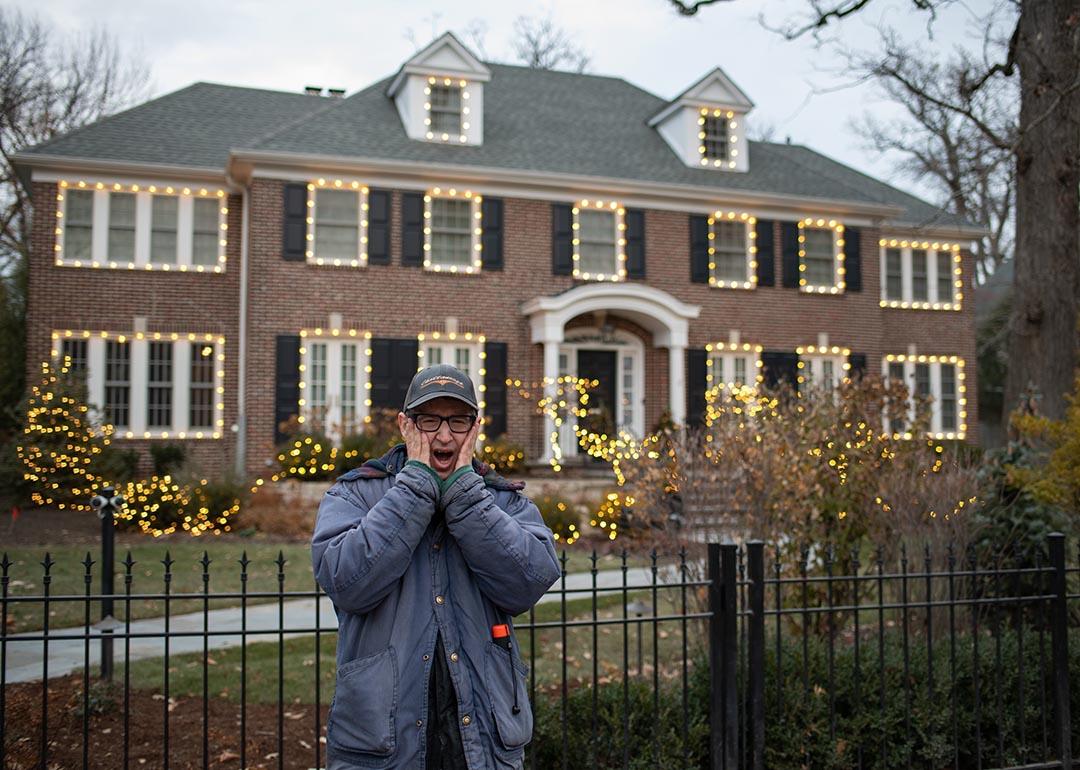 Person poses with the classic "Home Alone" pose with hands pressed to cheeks outside the gate of the home used in the film "Home Alone," in Winnetka, IL