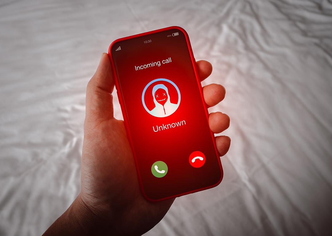A person's smartphone receiving an unknown call with a red alert.