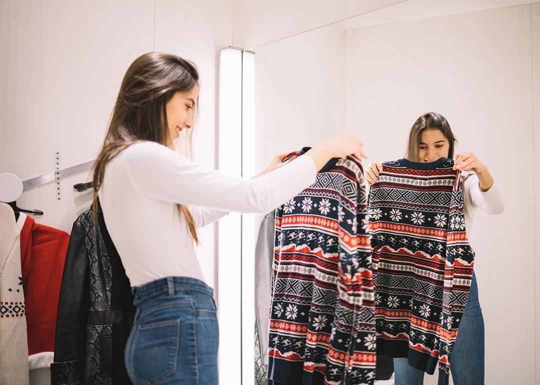 A young woman looking at a winter sweater in a dressing room.