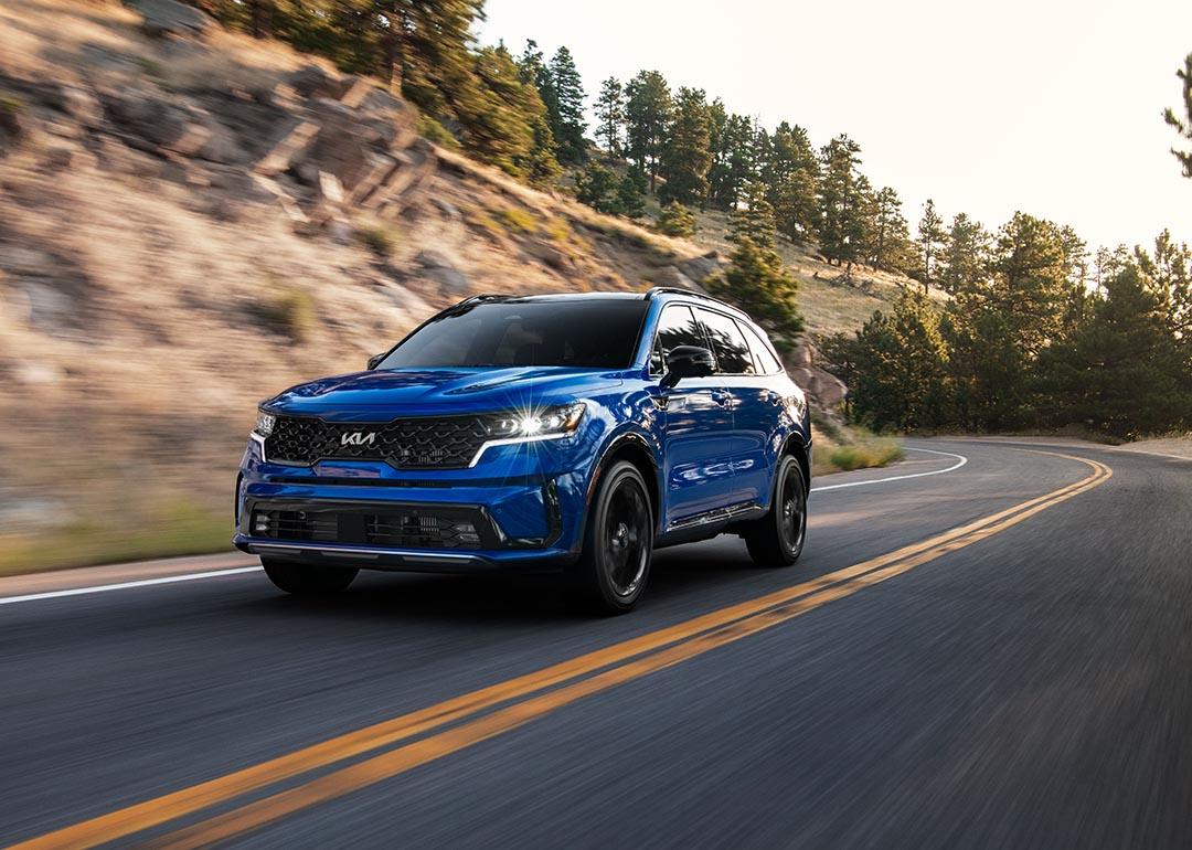 A front 3/4 view of a blue 2023 Sorento SX driving on a mountain road.