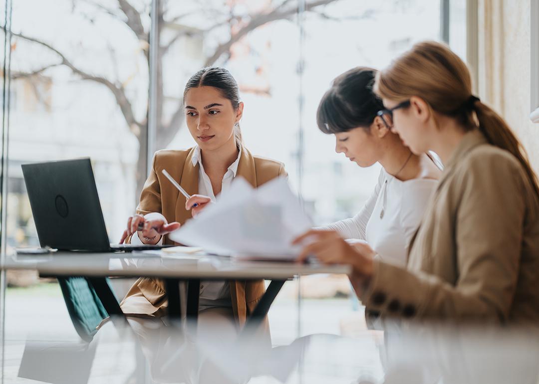 A group of three female professionals in a coworking space.