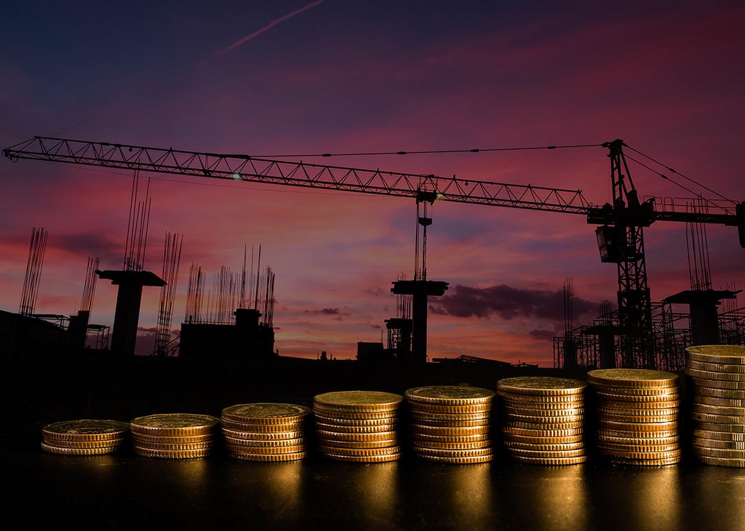 A row of stacked coins with an estate construction site background.