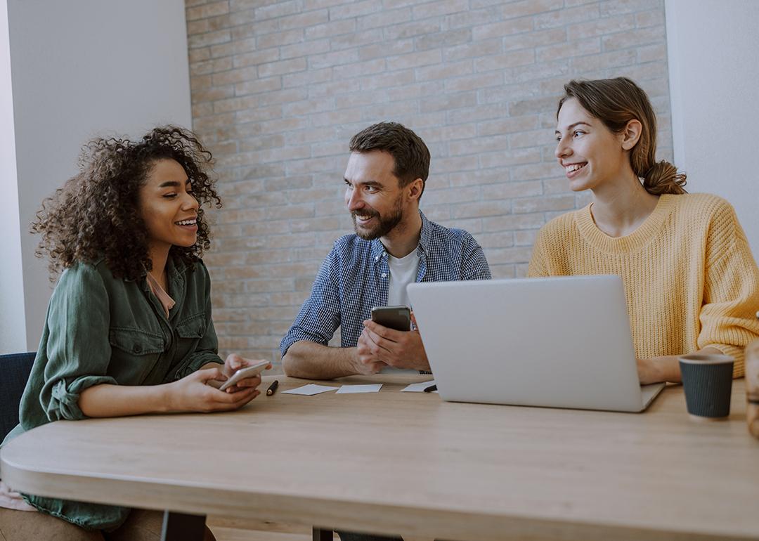A 3-member creative team engaged together in a discussion in an office.