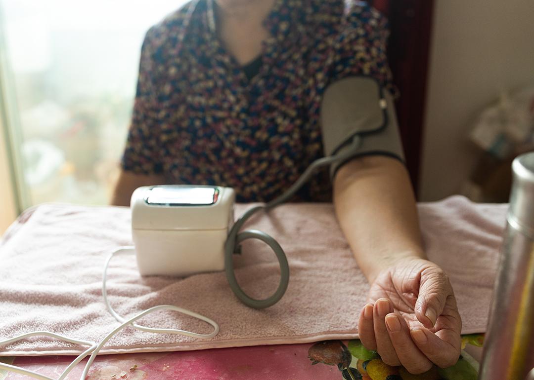 A senior woman getting her blood pressure checked using a digital monitor.