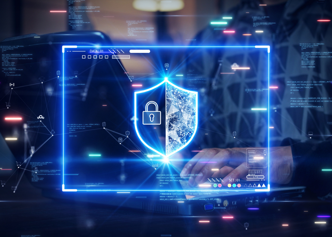 A person's hands type on a computer keyboard with a glowing security shield overlaid on the photo.