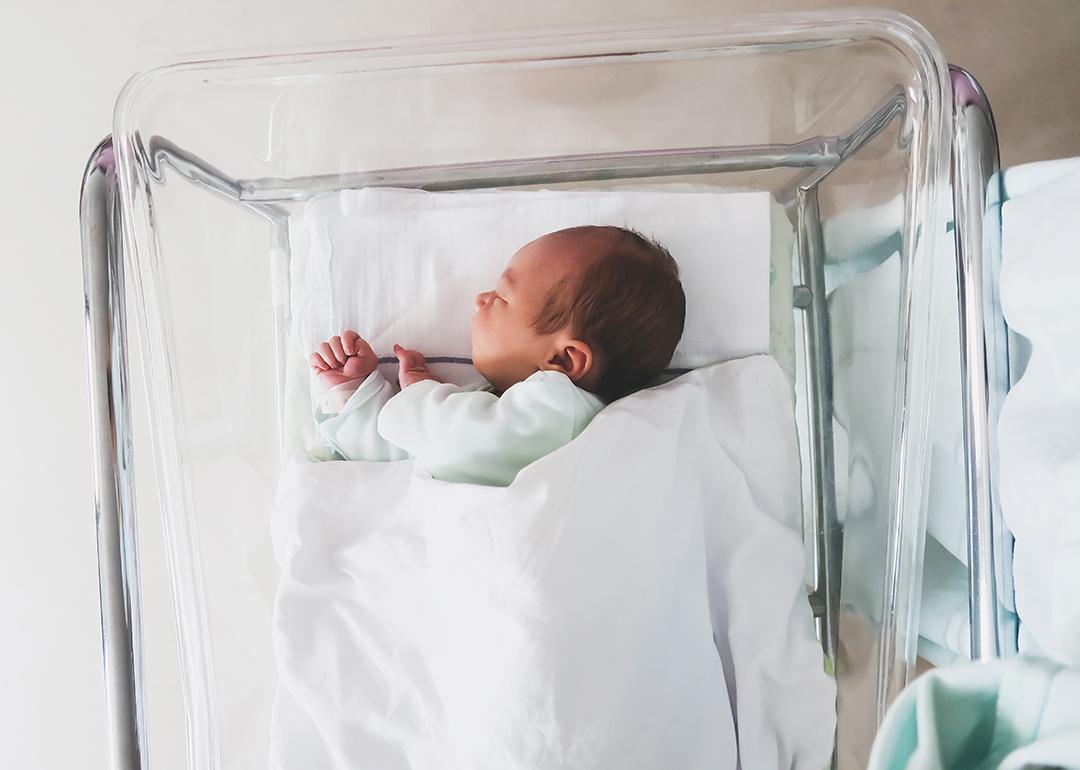 A newborn baby sleeping in a hospital crib.