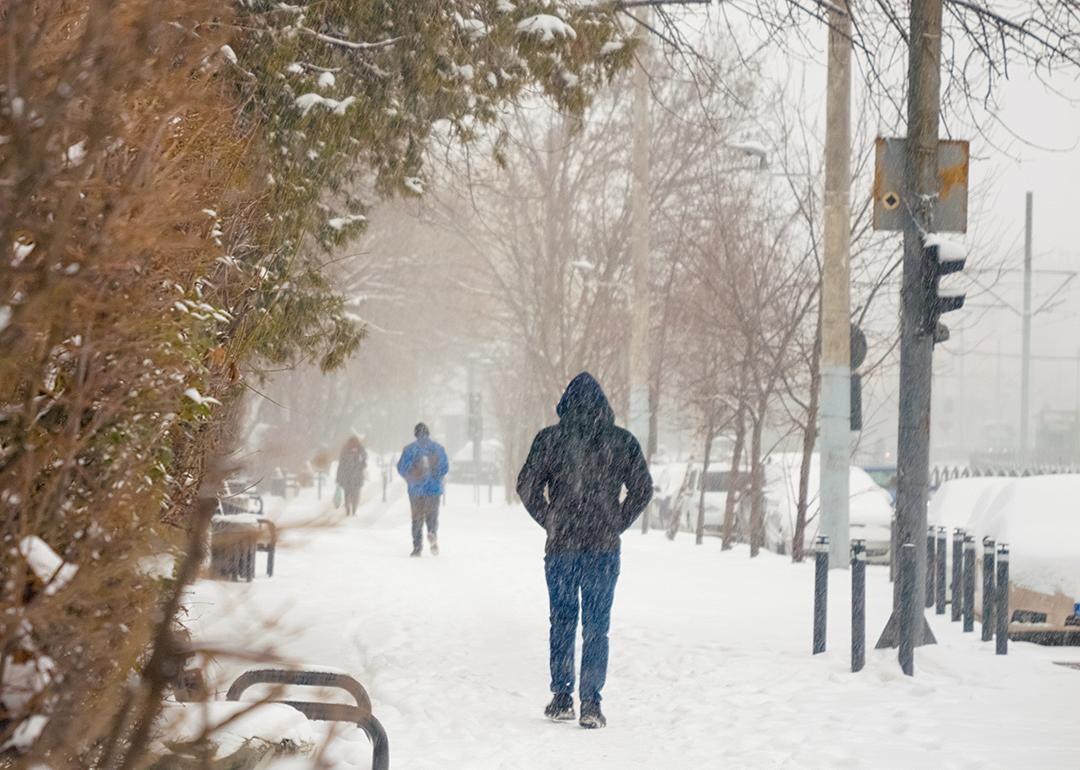 People walking through sidewalks during a heavy snowfall day.