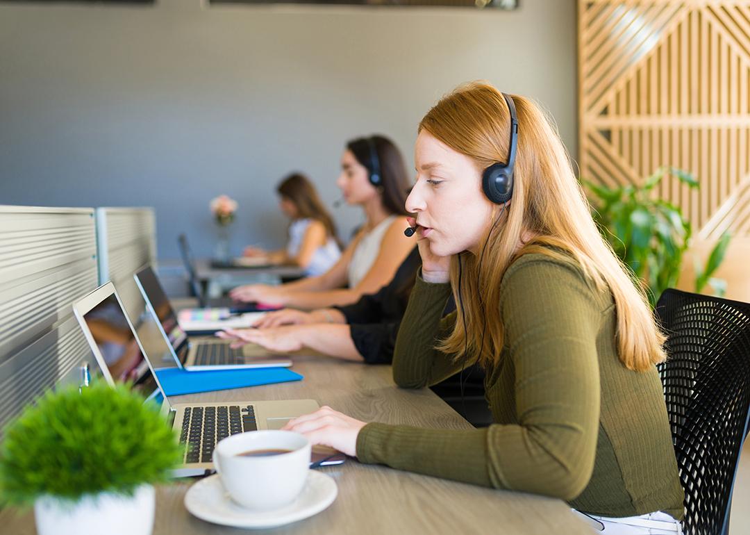 A row of female customer service representatives taking calls in their office.