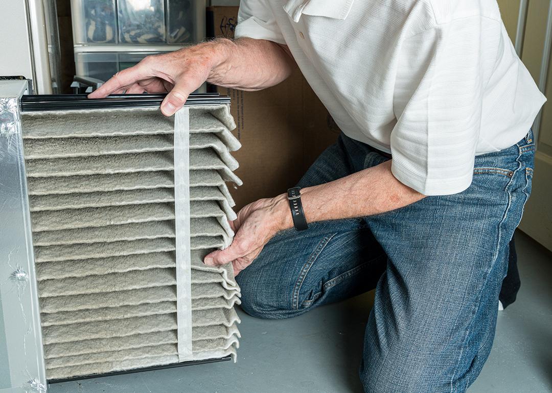Man changing a folded dirty air filter of an HVAC system.