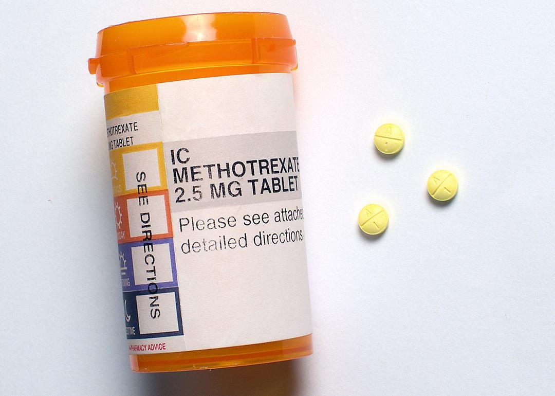 Three generic Methotrexate pills beside a prescription bottle.