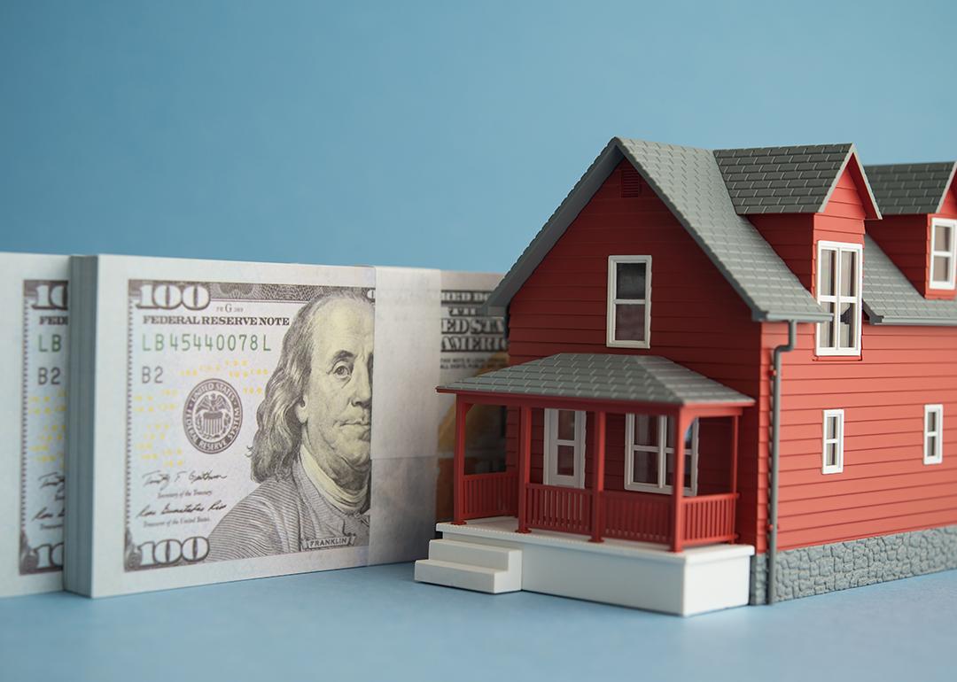 US dollar banknotes and a figure of a home.