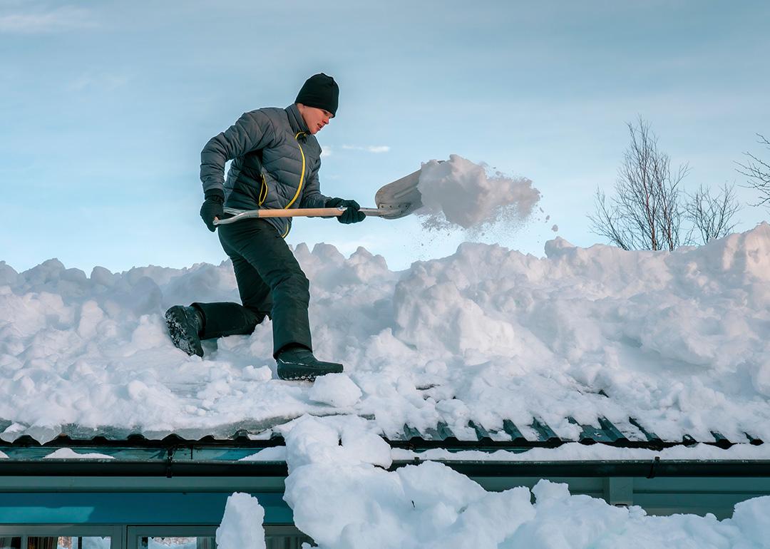 Young person shoveling heavy snow on a rooftop.