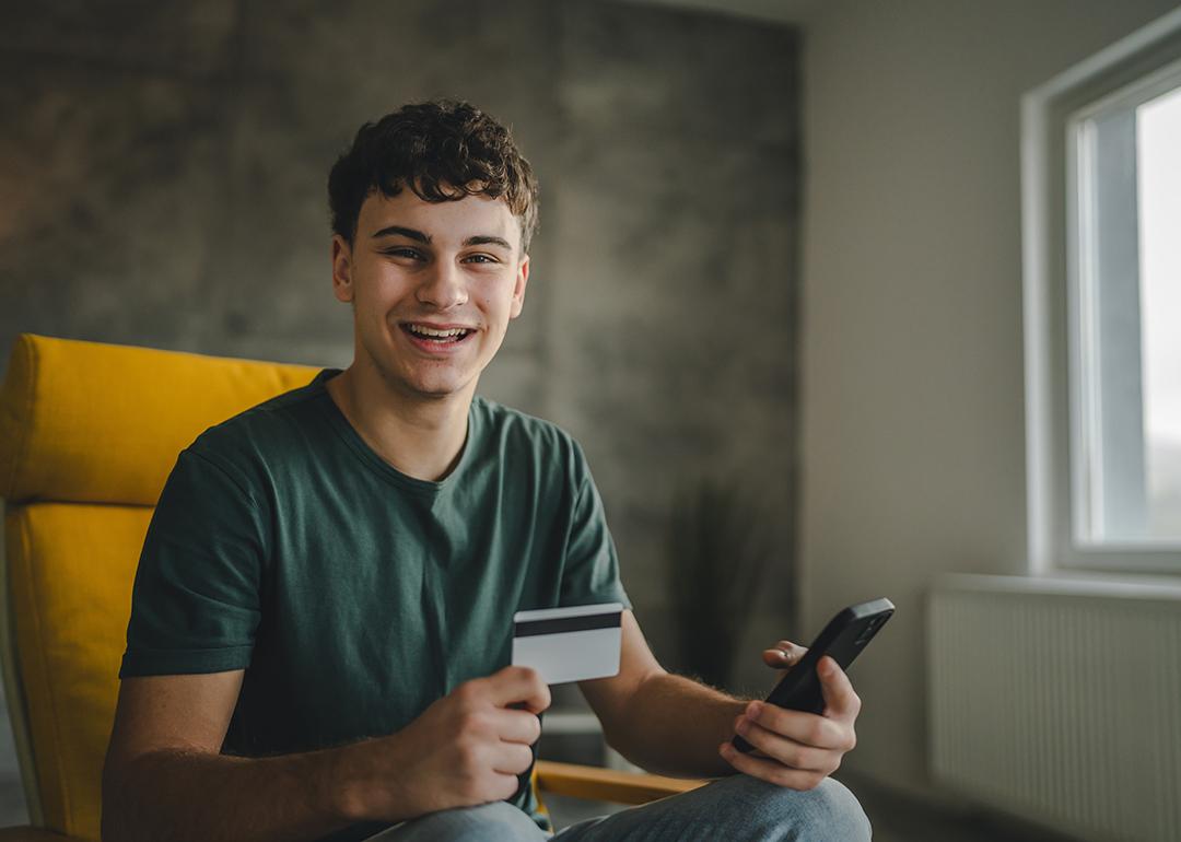 A happy young man using a credit card to purchase online.