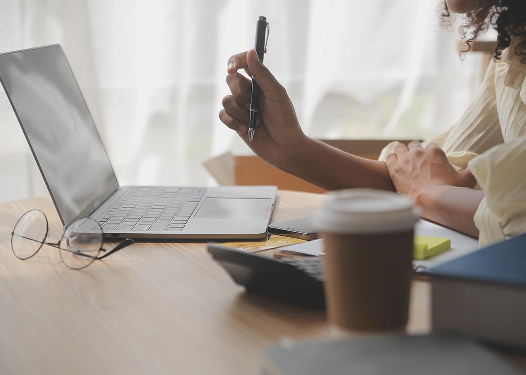 A female entrepreneur holding a pen while working with a laptop.