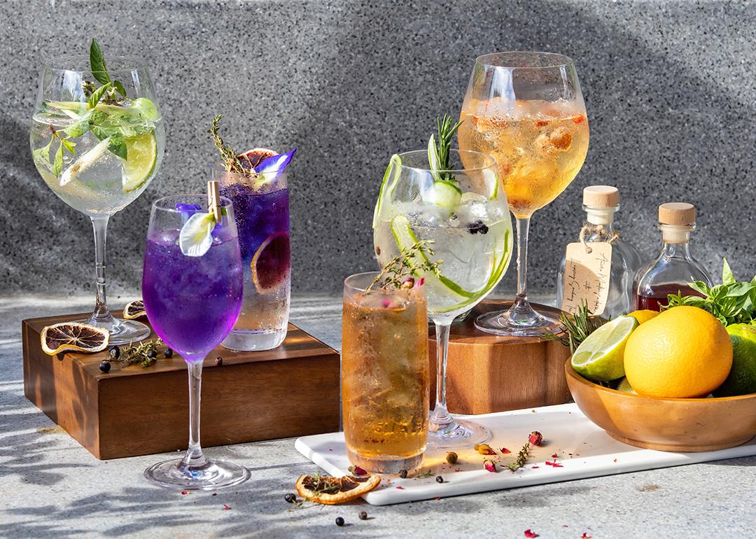 A display of assorted homemade herbal cocktails in wine glasses.