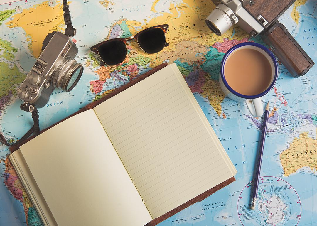 Traveller items such as a camera, sunglasses, and an empty planner on top of a world map.