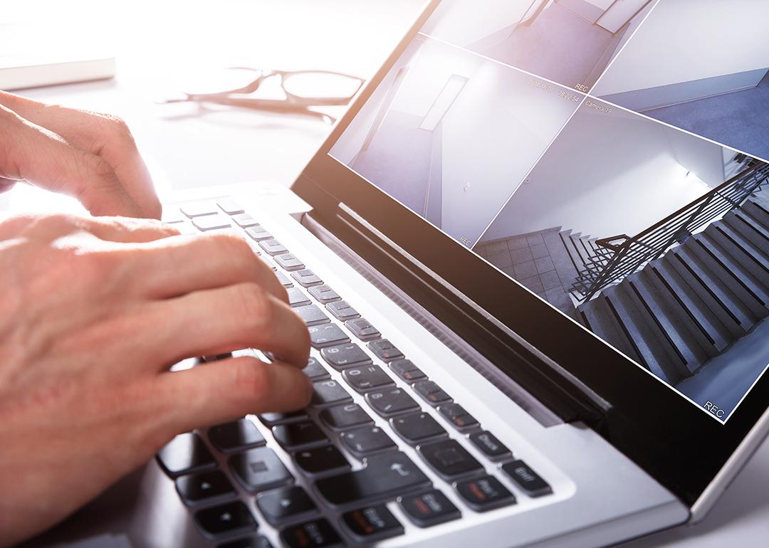 Person monitors a split screen view of CCTV footage using a laptop.