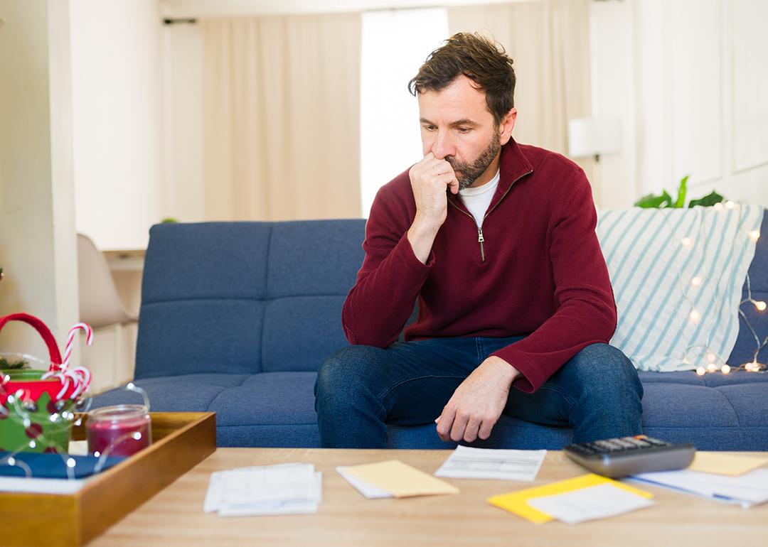 A worried man calculating expenses at home.
