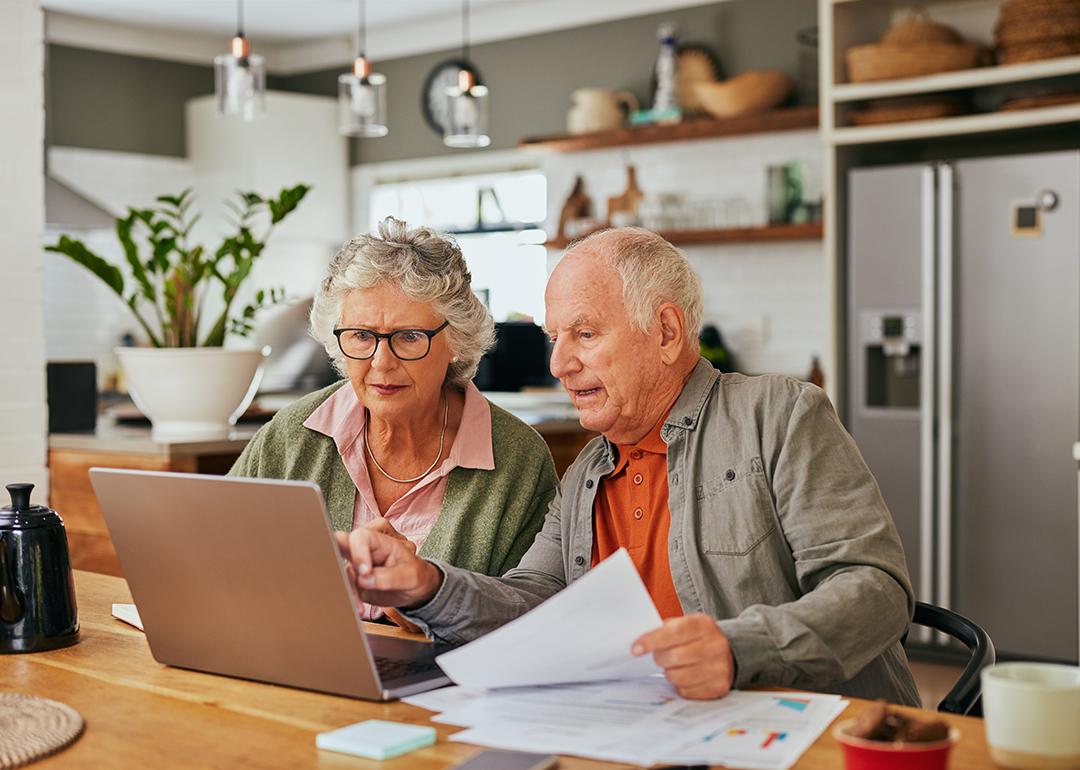 A senior couple using a laptop to review documents.