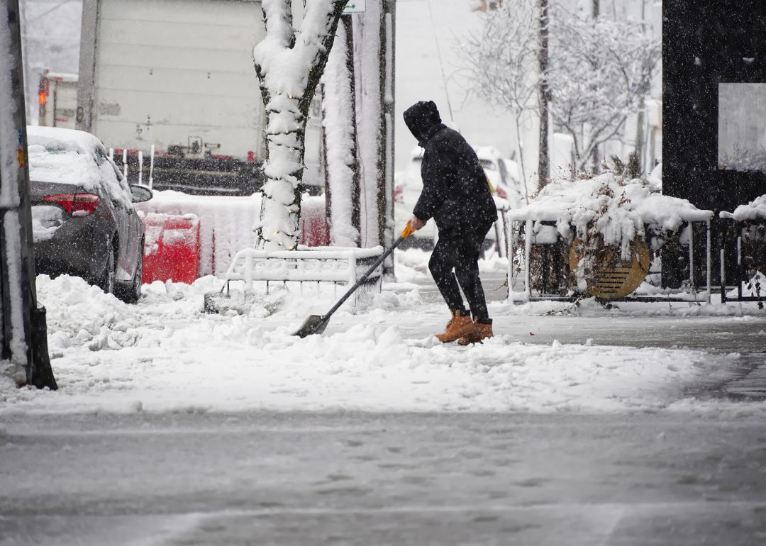 A person shovels snow in a neighborhood.