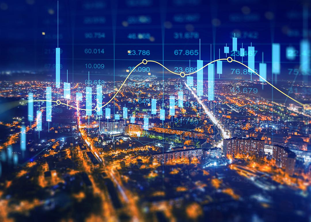 Aerial view of a city at night illustrated with holographic finance charts.