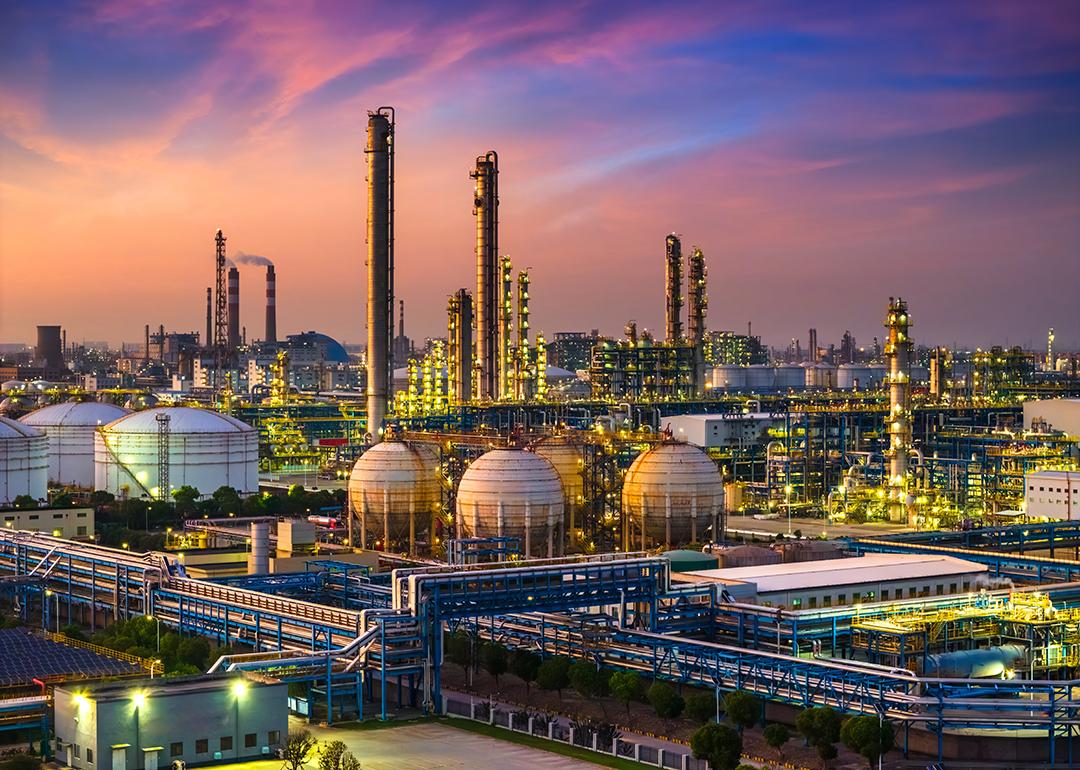 A view of a large industrial oil refinery and chemical plant during sunset.