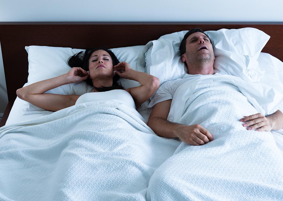 A couple sleeping in bed together where the wife is disturbed by her husband's snoring.