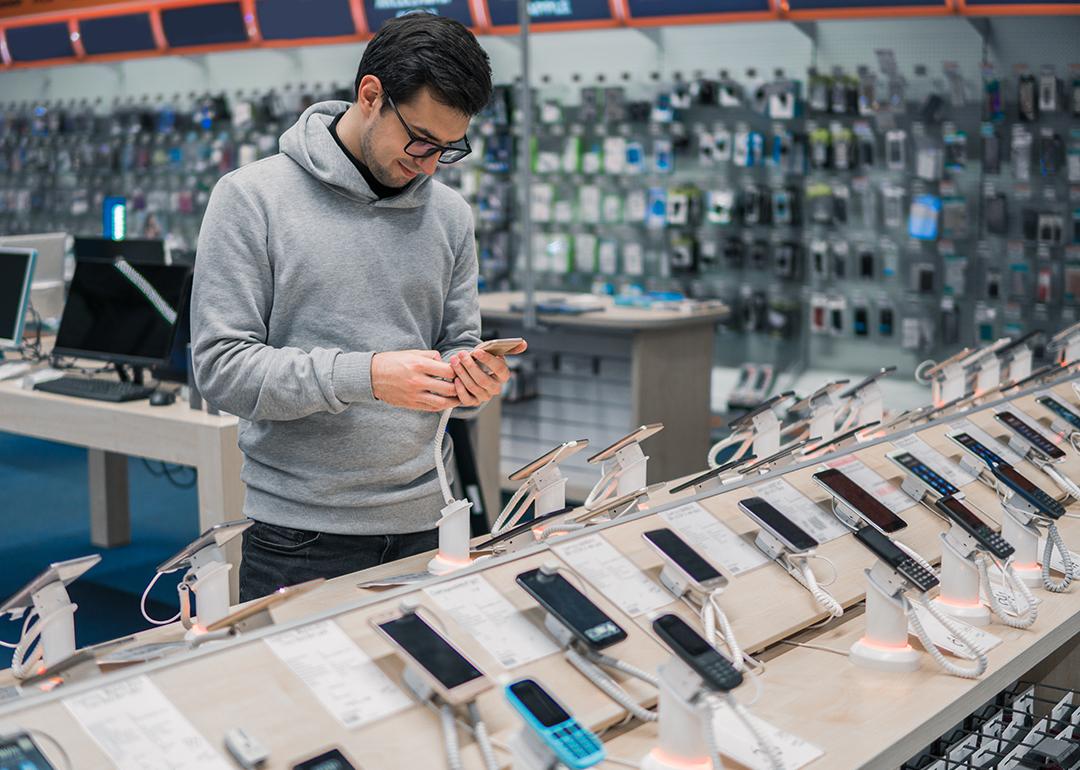 Man checking phone models at a store.