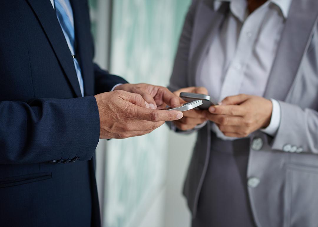 Two businesspeople on their phones exchanging numbers.